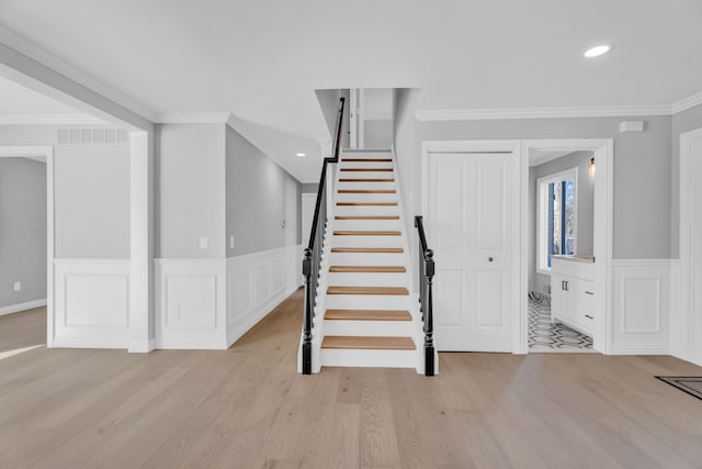 stairway with crown molding and wood-type flooring