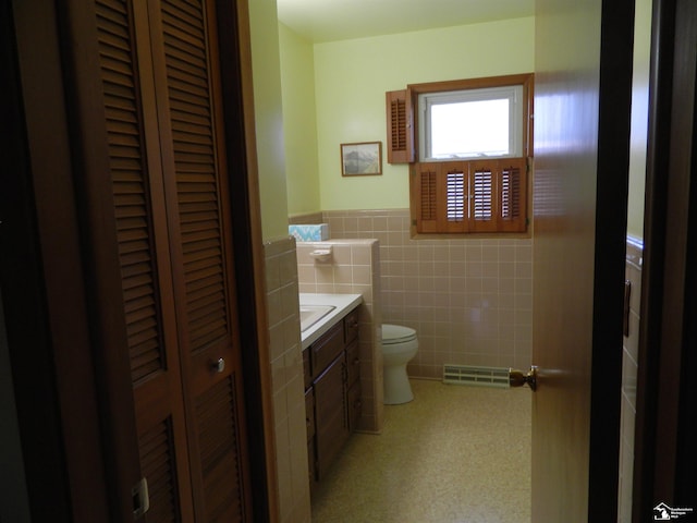 bathroom with tile walls, vanity, and toilet