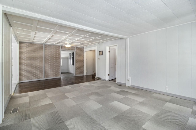 carpeted empty room featuring brick wall and ceiling fan