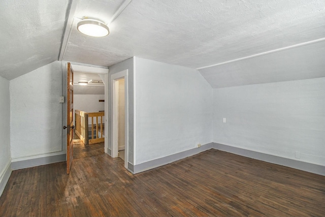 bonus room featuring dark hardwood / wood-style flooring, lofted ceiling, and a textured ceiling