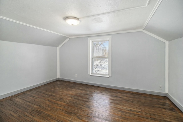 additional living space with dark hardwood / wood-style flooring, vaulted ceiling, and a textured ceiling