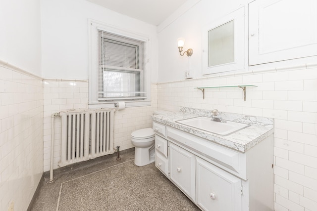 bathroom with vanity, toilet, radiator, and tile walls