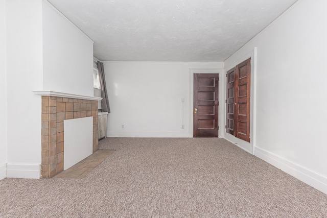 unfurnished living room with light carpet, a tiled fireplace, and a textured ceiling