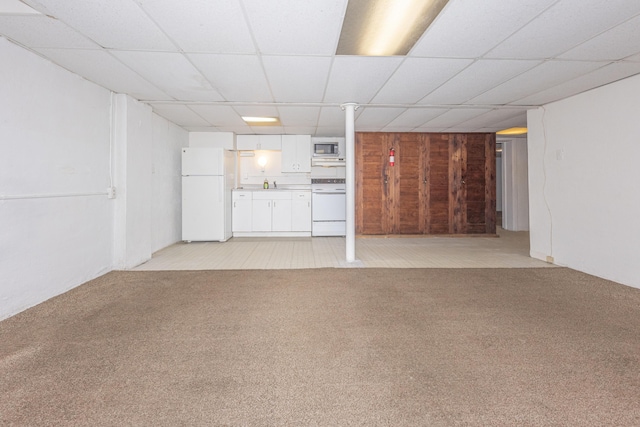 basement featuring white fridge, sink, light carpet, and a drop ceiling