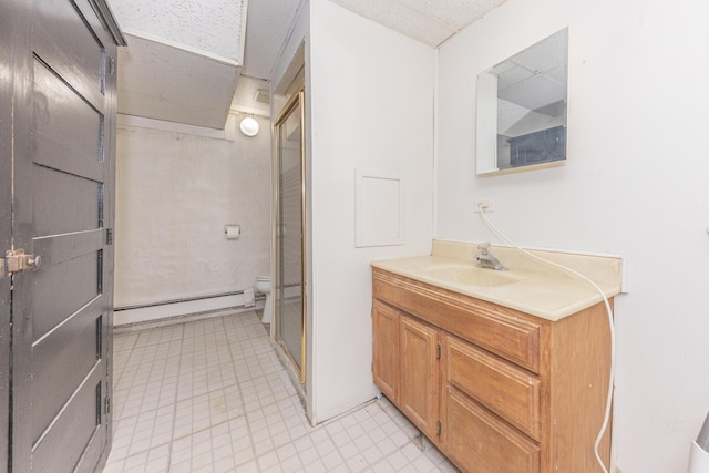 bathroom with a baseboard radiator, a drop ceiling, vanity, and toilet