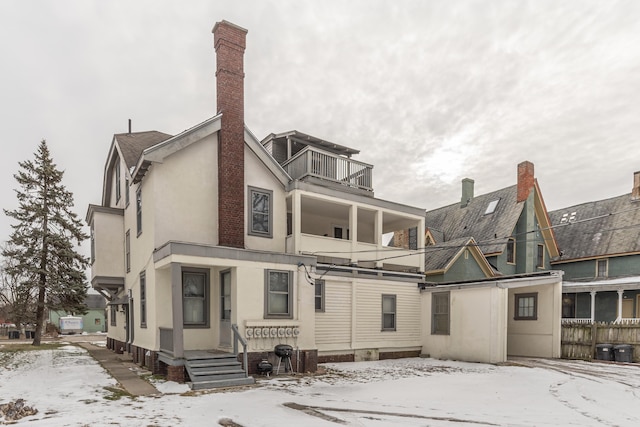 snow covered house featuring a balcony