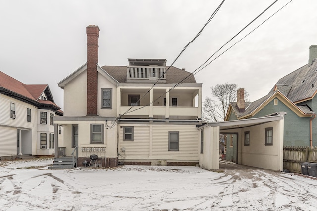 snow covered back of property featuring a balcony