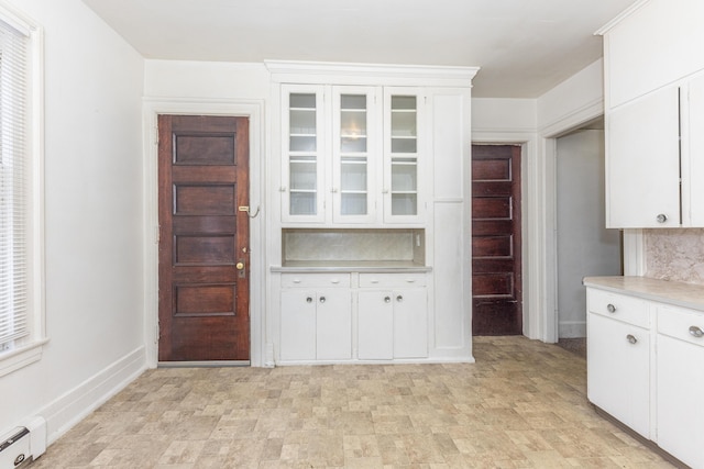 kitchen with a baseboard heating unit, white cabinets, and decorative backsplash