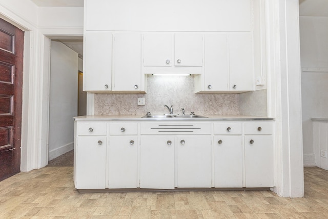 kitchen with backsplash, sink, and white cabinets