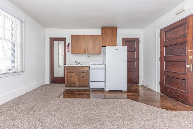 kitchen with crown molding, sink, white appliances, and dark colored carpet