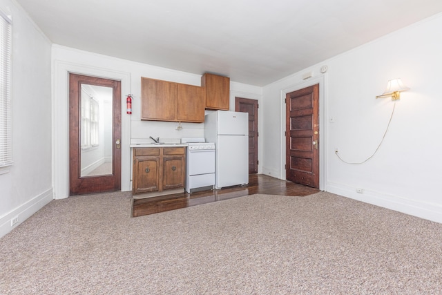 kitchen featuring white refrigerator, dark colored carpet, sink, and stove