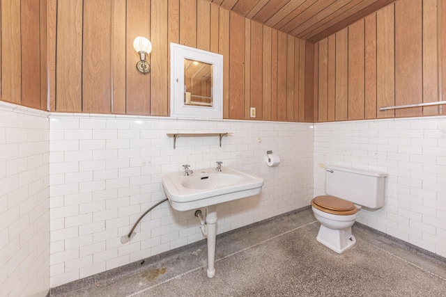 bathroom featuring sink, tile walls, and toilet