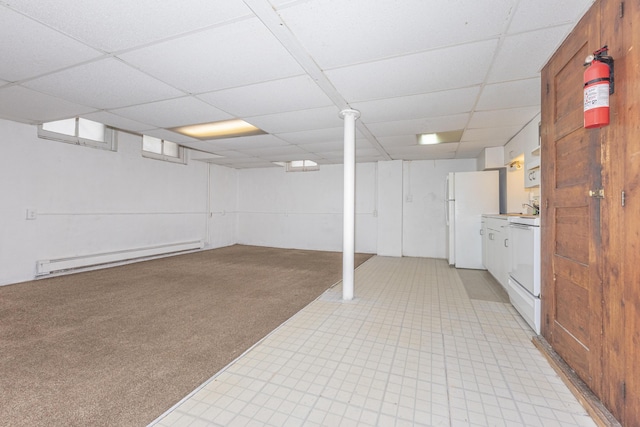 basement featuring white refrigerator, a baseboard radiator, light colored carpet, and a drop ceiling