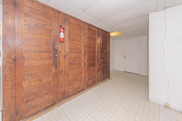 hall featuring a paneled ceiling and wood walls