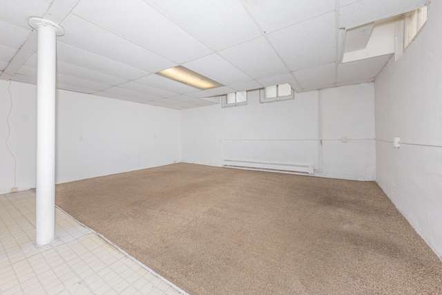 basement featuring a paneled ceiling, light carpet, and a baseboard heating unit