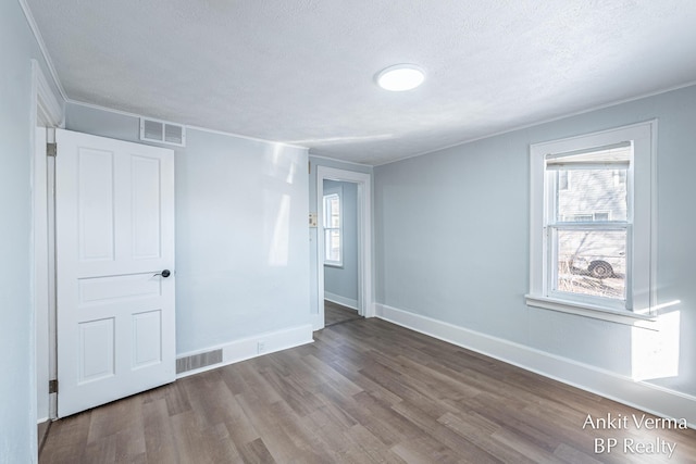 empty room with ornamental molding, hardwood / wood-style floors, and a textured ceiling