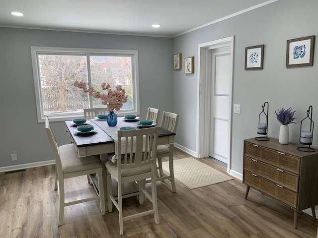 dining space with hardwood / wood-style flooring and ornamental molding