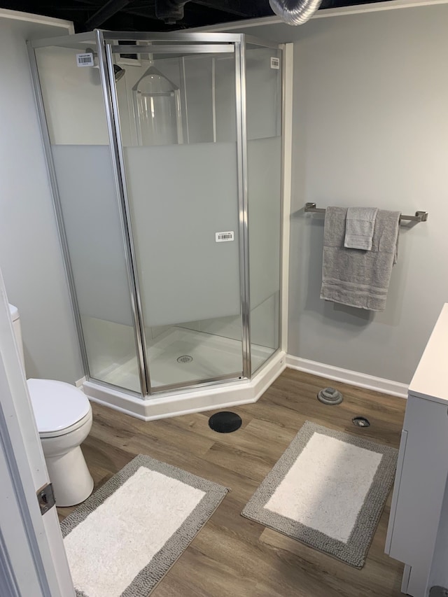 bathroom featuring a shower with door, hardwood / wood-style flooring, and toilet