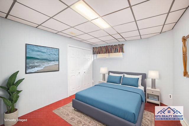 bedroom with carpet floors, a paneled ceiling, and a closet