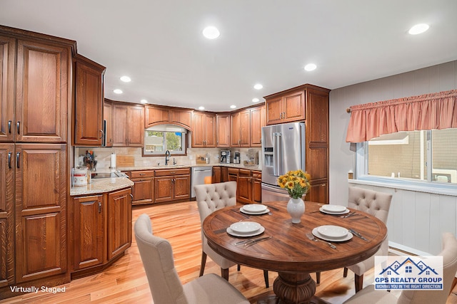 kitchen featuring sink, stainless steel appliances, tasteful backsplash, light hardwood / wood-style floors, and light stone countertops