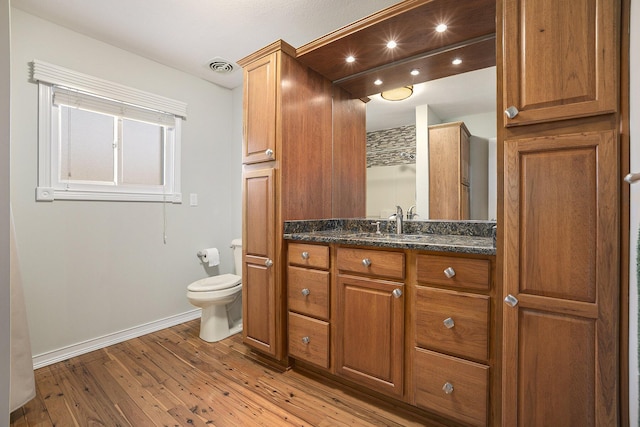 bathroom featuring wood-type flooring, toilet, and vanity