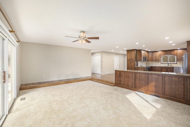 kitchen with sink, light carpet, dishwasher, kitchen peninsula, and decorative backsplash