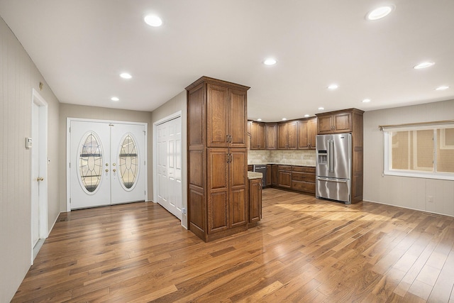 kitchen with decorative backsplash, high quality fridge, light hardwood / wood-style floors, and french doors