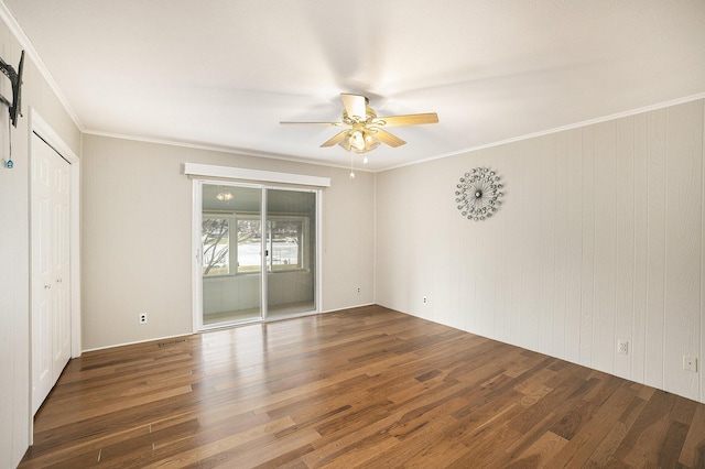 unfurnished bedroom featuring dark wood-type flooring, ceiling fan, ornamental molding, and a barn door