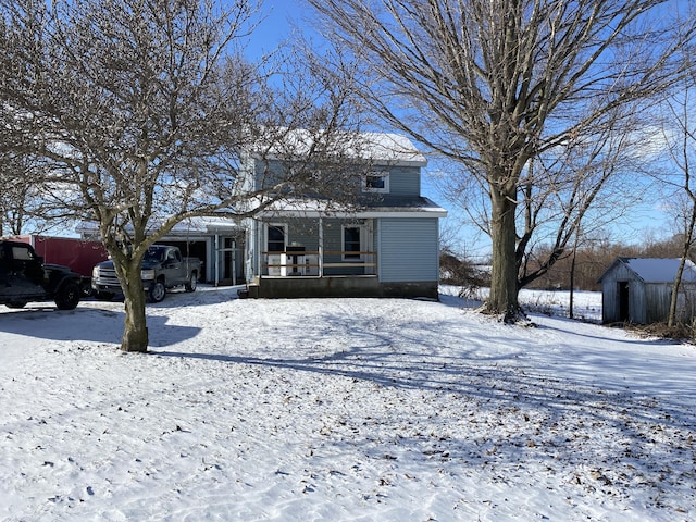 snow covered property featuring a shed and a porch