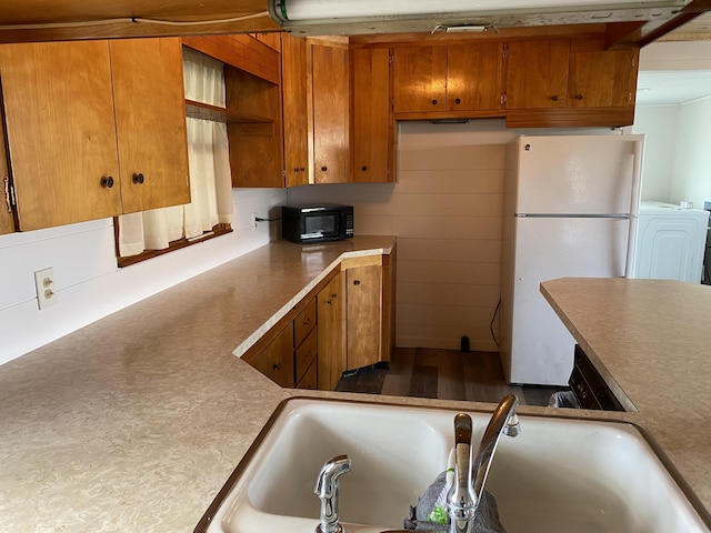 kitchen with washer / clothes dryer, white fridge, and sink