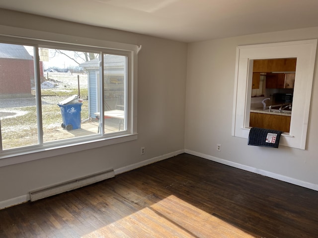 unfurnished room with dark hardwood / wood-style floors, a healthy amount of sunlight, and baseboard heating