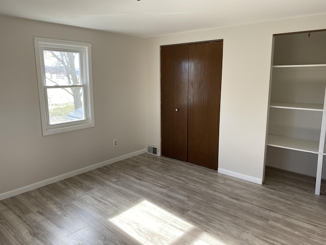 unfurnished bedroom with multiple closets and light wood-type flooring