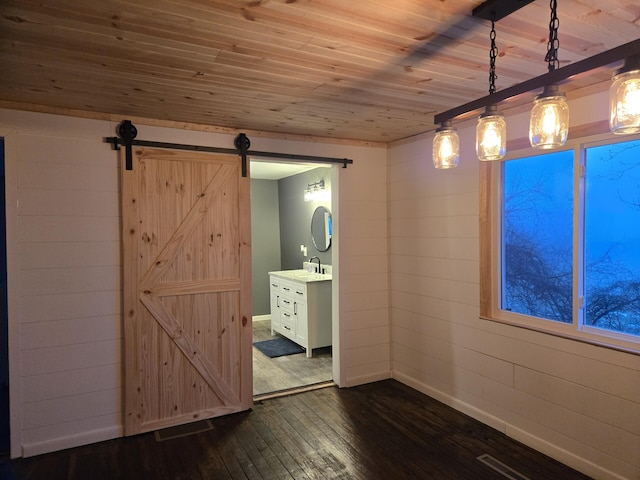 unfurnished dining area with wood ceiling, dark hardwood / wood-style floors, a barn door, and wooden walls