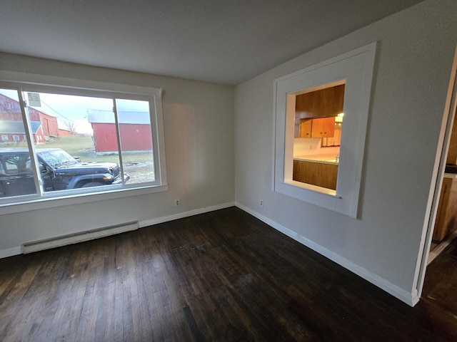 empty room with baseboard heating and dark hardwood / wood-style floors