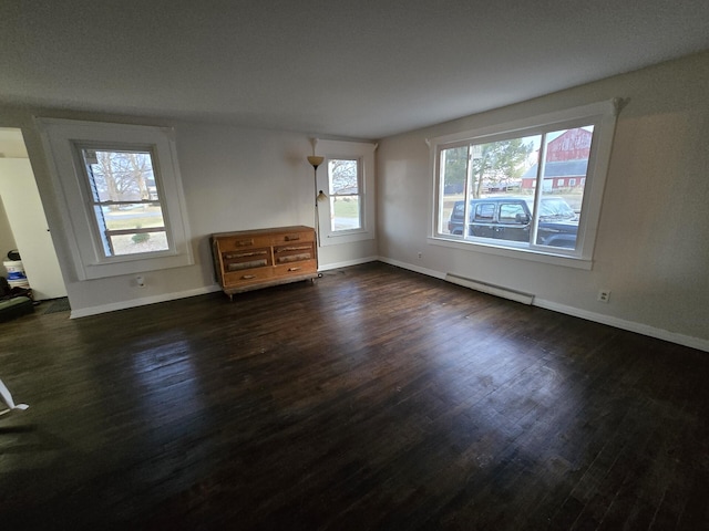 unfurnished room with dark hardwood / wood-style floors and a baseboard heating unit