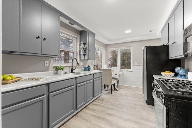 kitchen featuring gray cabinetry, sink, light hardwood / wood-style flooring, and gas stove