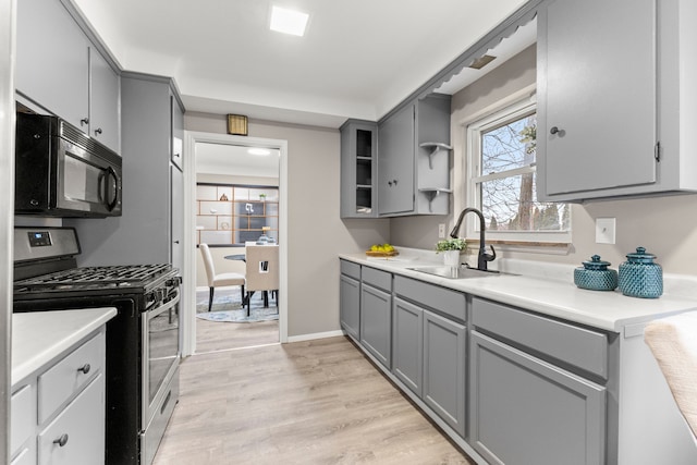 kitchen with gray cabinetry, sink, stainless steel gas range, and light hardwood / wood-style floors