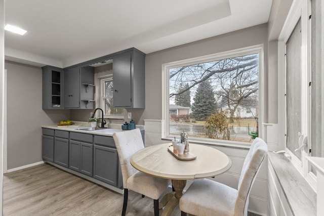 kitchen with a healthy amount of sunlight, sink, gray cabinetry, and light hardwood / wood-style floors