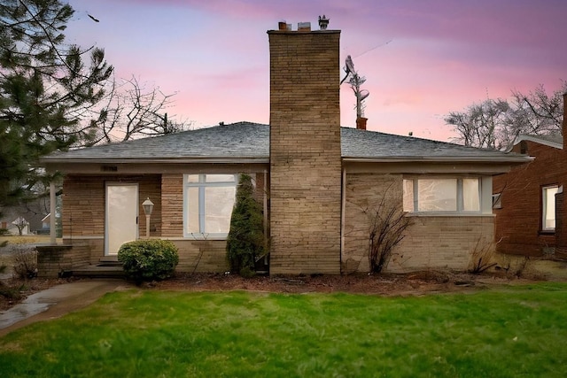 back house at dusk with a lawn