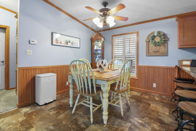 dining space with crown molding, ceiling fan, and wood walls