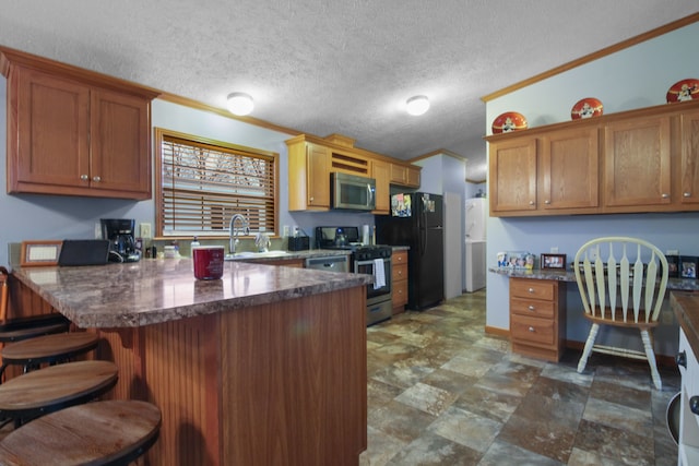 kitchen featuring sink, crown molding, a breakfast bar area, appliances with stainless steel finishes, and built in desk