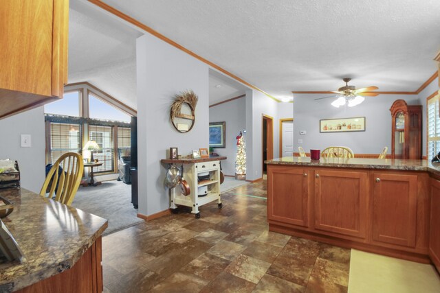 kitchen featuring ornamental molding, dark stone countertops, a textured ceiling, and ceiling fan