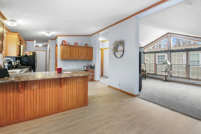 kitchen featuring sink, appliances with stainless steel finishes, ornamental molding, kitchen peninsula, and light wood-type flooring