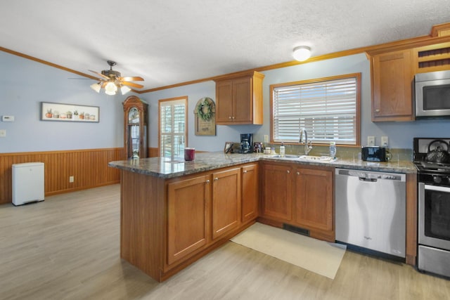 kitchen with sink, stainless steel appliances, kitchen peninsula, and light wood-type flooring