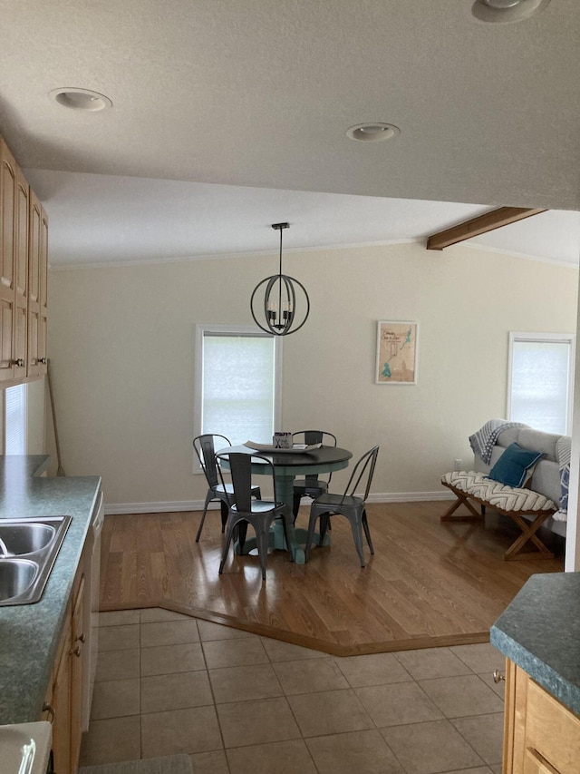 dining space featuring lofted ceiling, sink, light tile patterned floors, and an inviting chandelier