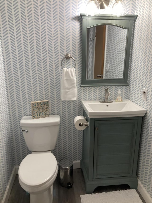 bathroom with vanity, toilet, and hardwood / wood-style floors