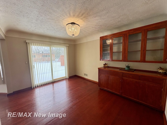 unfurnished dining area with dark wood-type flooring and a textured ceiling