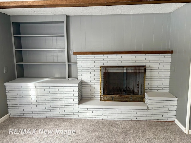 interior details featuring built in shelves, a brick fireplace, and carpet