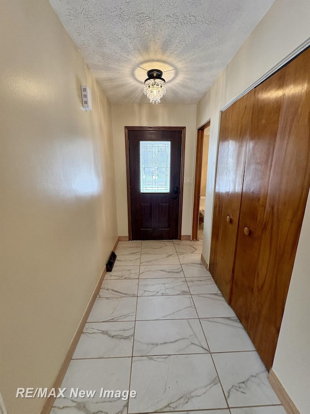 entryway with a notable chandelier and a textured ceiling