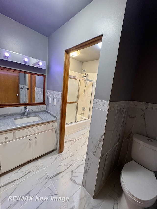 bathroom featuring vanity, a shower with shower door, tile walls, and toilet